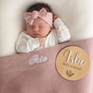 Personalised Blush Pink Blanket and 3D Baby Name Disc with girl laying underneath.
