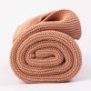 Dusty Peach Knitted Personalised Baby Blanket rolled up and photographed side on.