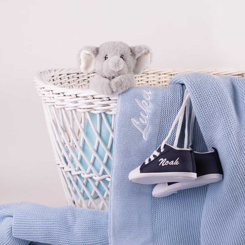 Personalised blue baby boy gift items with embroidery, hanging on a basket.