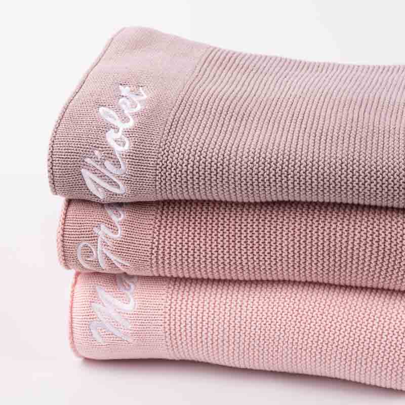 Three personalised baby blankets for girls folded atop each other.