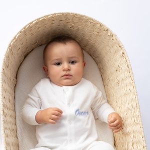 Baby in basket wearing personalised white cotton onesie for boys.