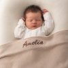 Baby sleeping under personalised beige knitted blanket present for newborns.