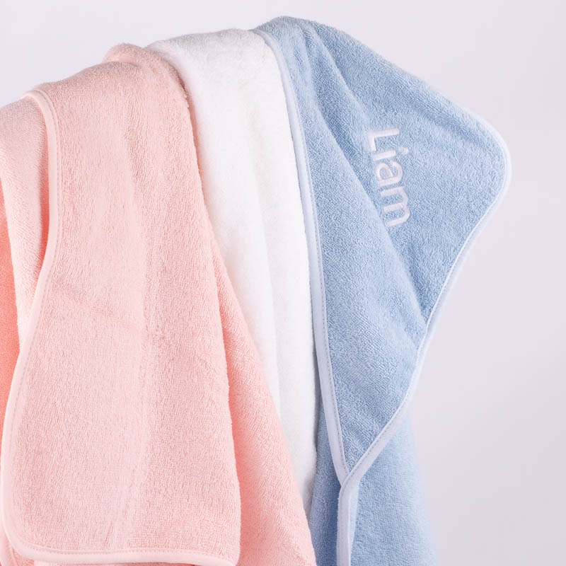 Personalised baby towels hanging up with name embroidery showing on the blue towel.