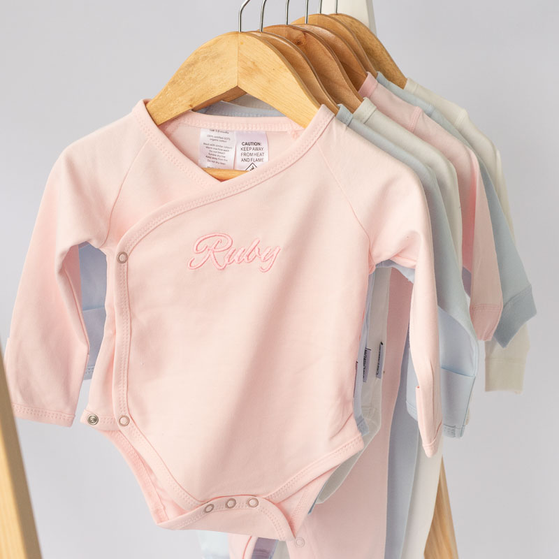 Personalised Pink Baby Romper hanging on a coat hanger. Perfect for everyday wear.