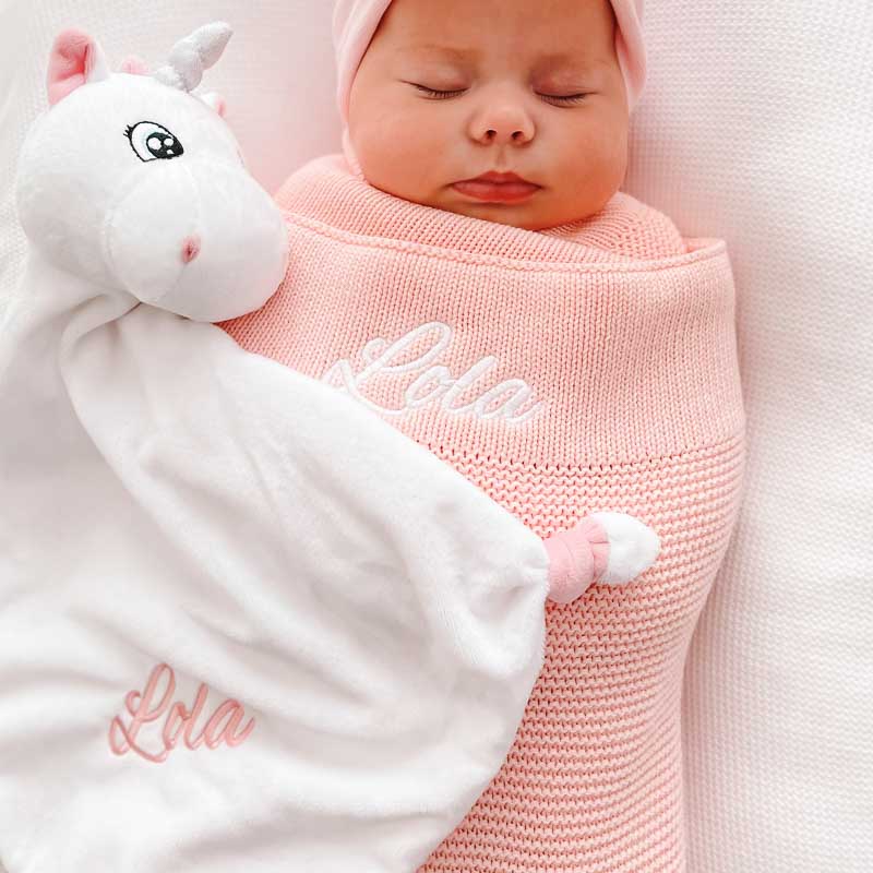 Baby sleeping and wrapped in Personalised Pink knitted baby blanket with unicorn.