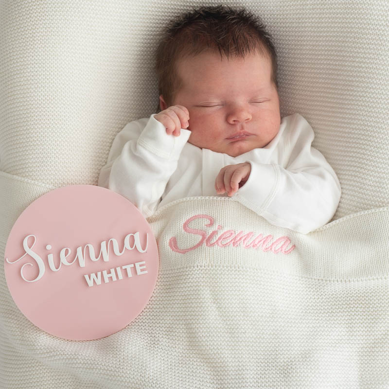 Personalised white knitted blanket and pink acrylic baby name plaque.