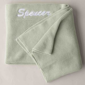 A green knitted baby blanket personalised with the name Spencer.