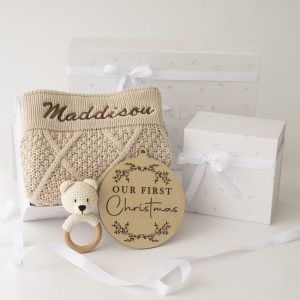 A personalised beige diamond baby blanket with a bear rattle and Christmas disc.