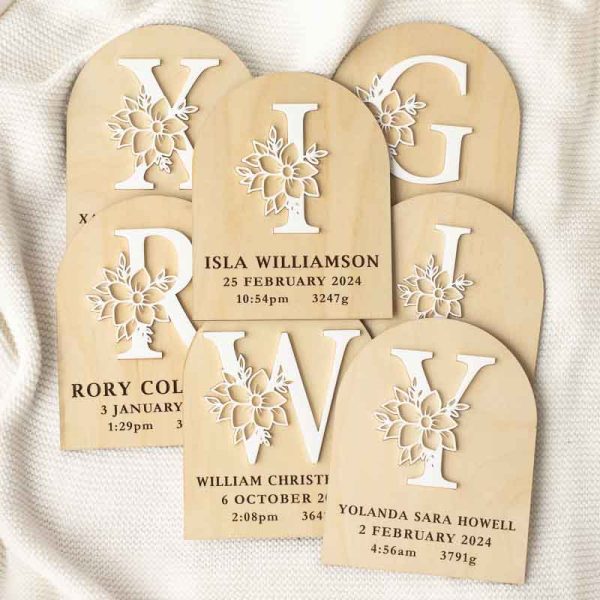 A group of birth announcement discs featuring a capitalised letter with a flower in acrylic.