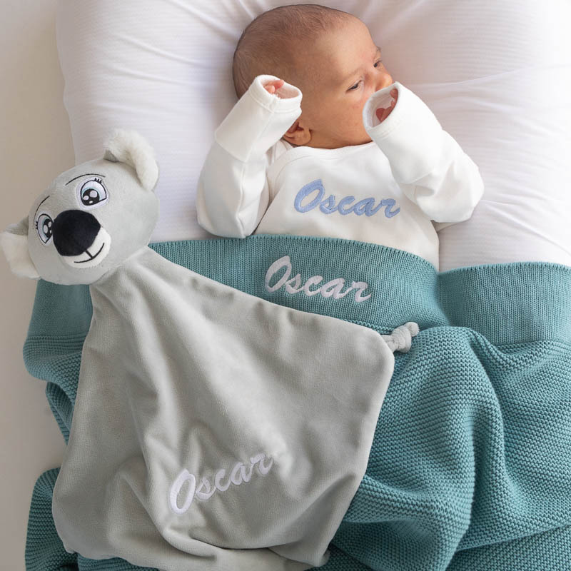 Baby with personalised ocean blue blanket and koala comforter embroidered with Oscar.