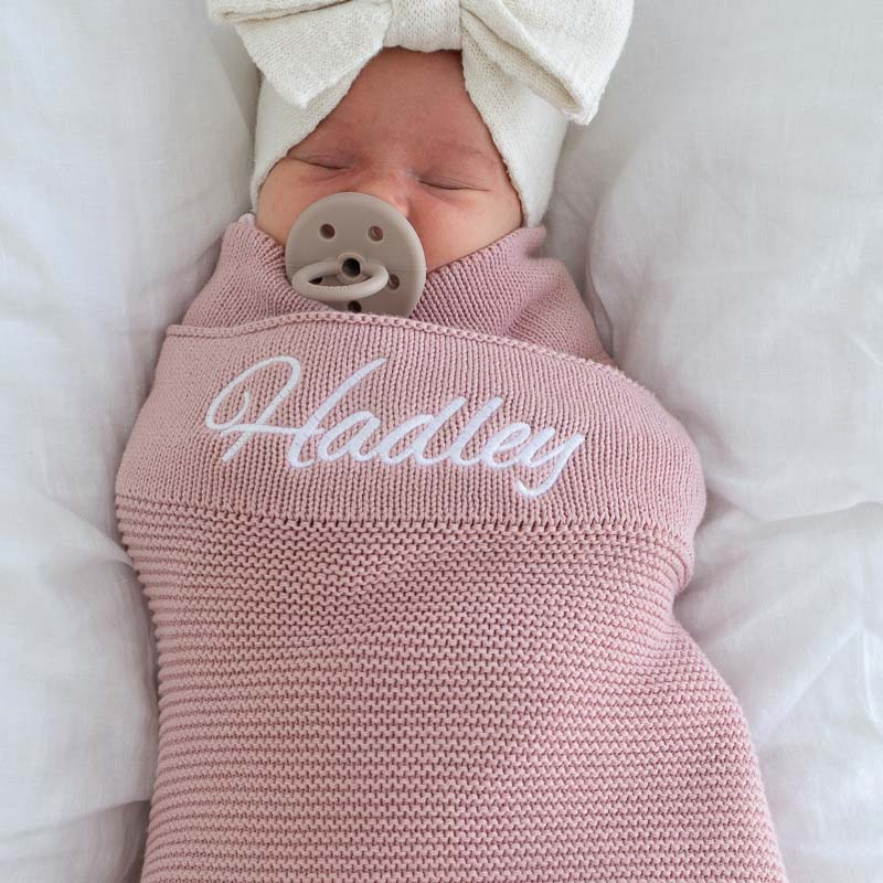 Girl wrapped in blush pink personalised baby blanket.